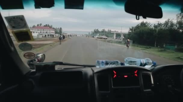 KISUMU, KENIA - 14 DE MAYO DE 2018: Vista desde el interior del coche a través del parabrisas. Conductor a caballo a través de la carretera del país, a través de aldea en África . — Vídeo de stock