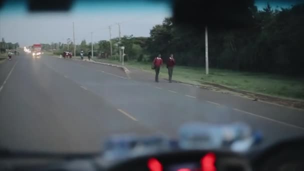 Kisumu, Keňa - 14. května 2018: Pohled z uvnitř auta. Auto pojede podél venkovské silnici. Africké děti a lidé jsou na cestě. — Stock video