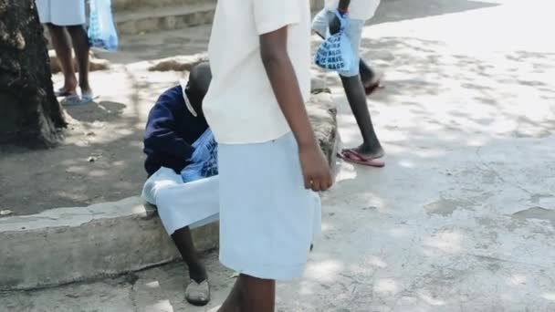 KISUMU, KENIA - 15 DE MAYO DE 2018: Chica africana calva sentada afuera cerca de la escuela y mirando dentro de la bolsa, presente abierto . — Vídeos de Stock