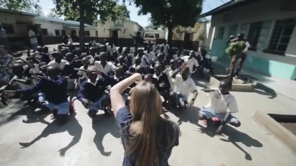 Kisumu, Kenia - mei 15, 2018: Menigte dansen buiten in Afrika. Kaukasische vrouw tonen moties Afrikaanse kinderen — Stockvideo
