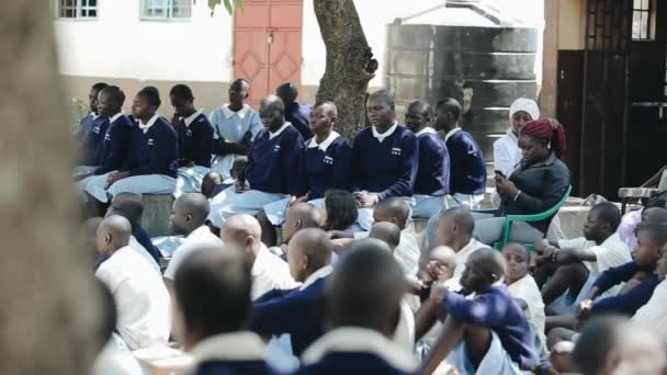 KISUMU, KENIA - 15 DE MAYO DE 2018: Grupo de niños y adolescentes africanos en uniforme sentados en el patio trasero de la escuela y mirando — Vídeos de Stock