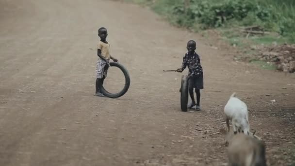 Kisumu, Kenya - 2018. május 15.: Két afrikai fiú játék-val abroncsok úton. Gyerekek, közösen szórakoztunk. — Stock videók