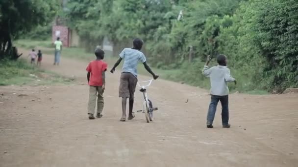 Kisumu, Kenya - 2018. május 17.: Hátsó nézet fiúk séta az út Afrikában. Férfi kerékpár, séta az erdő. — Stock videók