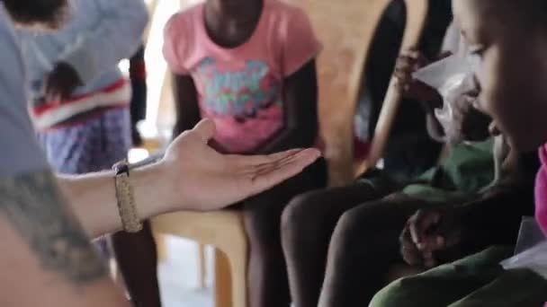 Kisumu, Kenia - mei 19, 2018: Groep weinig gelukkige kinderen uit Afrika en Kaukasische vrijwilliger in arme dorp. — Stockvideo