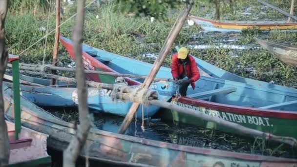 KISUMU, KENIA - 21 DE MAYO DE 2018: El hombre africano está trabajando en un barco en el puerto. Hermoso paisaje de la naturaleza y barcos cerca de la orilla . — Vídeos de Stock