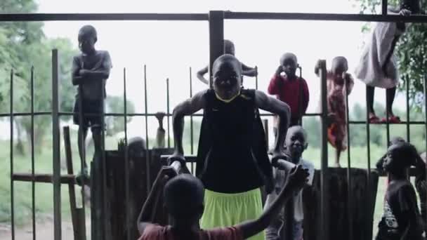 KISUMU, KENIA - 21 DE MAYO DE 2018: Adolescentes africanos bombean sus músculos en la barra horizontal afuera, en el campo de deportes . — Vídeo de stock