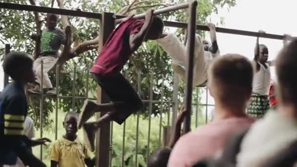 Kisumu, Kenia - mei 21, 2018: Afrikanen jongens op de horizontale balk omhoog te trekken. Tieners doen oefening buiten. — Stockvideo