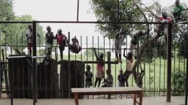 Kisumu, Kenya - 21 Mayıs 2018: Grup çocuk Afrika tırmanış ve çit otur. Erkek ve kız dışında vakit geçirmek