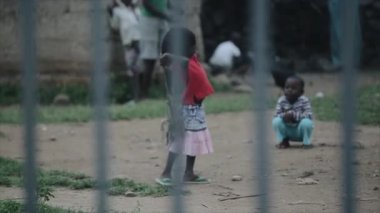 Kisumu, Kenya - 21 Mayıs 2018: Çitin üzerinden görünümü. Küçük kız Afrika'dan bir ev yapımı atlama ip atlar.