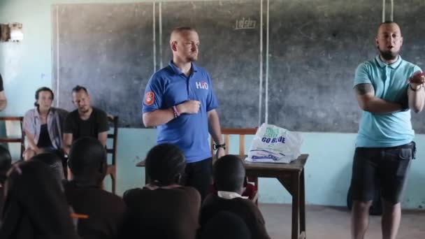 KISUMU, KENYA - 21 de maio de 2018: Homem e tradutor caucasiano em sala de aula cheia de crianças na escola africana . — Vídeo de Stock