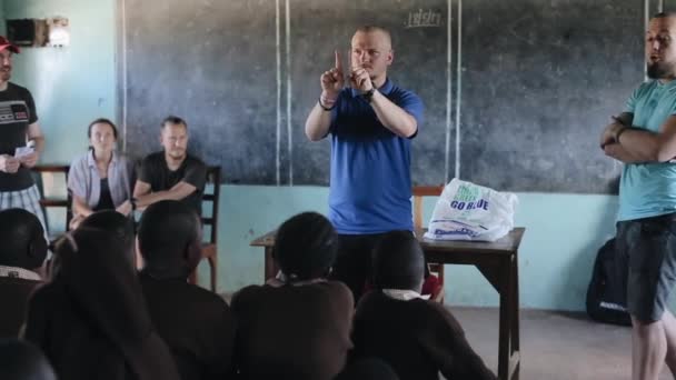 Kisumu, Kenya - 21 maj 2018: Kaukasiska man visar tricks till afrikanska barn i liten skola, skämt med dem. — Stockvideo