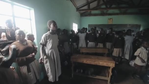 Kisumu, Kenya - 2018. május 21.: Kaukázusi önkéntesek a szegény afrikai iskola. Boldog fiúk és a lányok énekelni a dalt, taps kezek és a tánc. — Stock videók