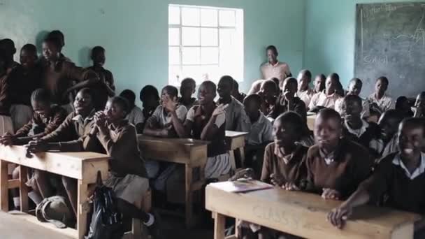 Kisumu, Kenya - 21 Mayıs 2018: Kalabalık kel Afrika çocukların okul sıraları oturuyorsun. Baylar bayanlar, gençler üniformalı — Stok video