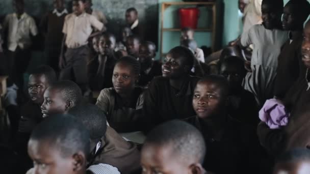 KISUMU, KENYA - MAY 21, 2018: Gruppe med afrikanske barn i uniform sitter i klasserommet og ser rett ut og smiler . – stockvideo