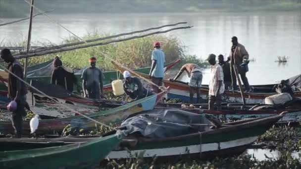 KISUMU, KENIA - 21 DE MAYO DE 2018: Grupo de hombres africanos en embarcaciones en el puerto, en la playa. Los jóvenes van a trabajar por la mañana. . — Vídeos de Stock