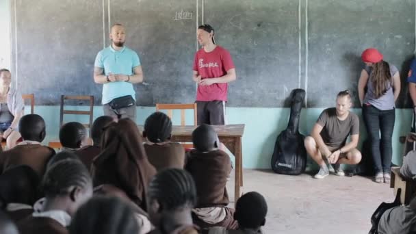 KISUMU, KENIA - 21 DE MAYO DE 2018: Grupo de personas caucásicas, voluntarios en la escuela africana, hablar con niños, contar algo — Vídeo de stock