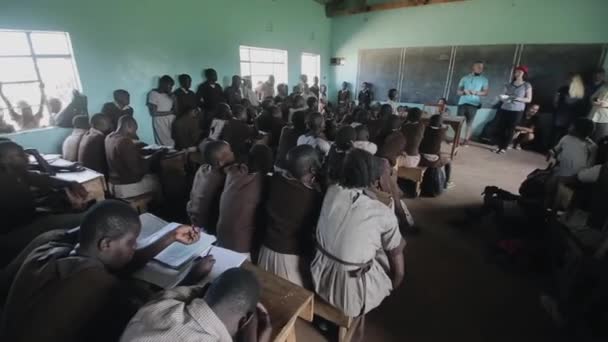 KISUMU, KENYA - 21 MAGGIO 2018: Gruppo di volontari caucasici in una piccola scuola in Africa. I bambini ascoltano in un'aula . — Video Stock