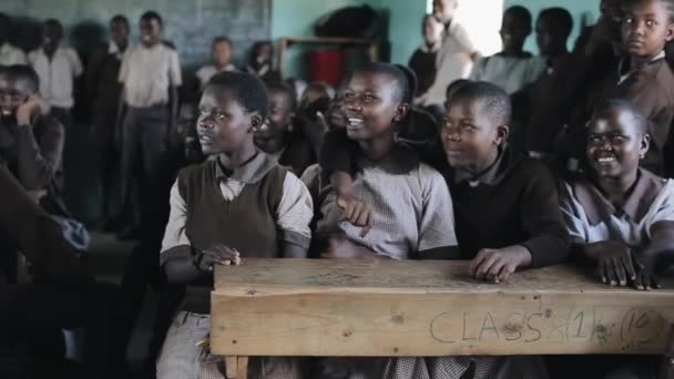 Kisumu, kenya - 21. Mai 2018: Gruppe fröhlicher afrikanischer Kinder sitzt im Klassenzimmer und lächelt, lacht zusammen. — Stockvideo