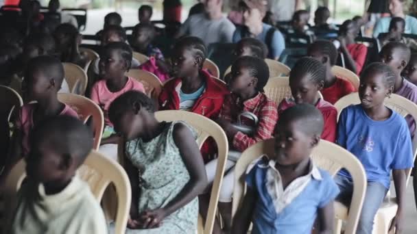 KISUMU, KENYA - 21 MAGGIO 2018: Un gruppo di bambini, ragazzi e ragazze africani si siede in una grande sala in attesa . — Video Stock
