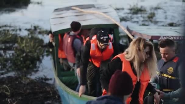 KISUMU, KENIA - 21 DE MAYO DE 2018: Grupo de jóvenes en chalecos salvavidas que salen del barco hacia la costa en África. Grupo de turistas que viajan por mar . — Vídeos de Stock