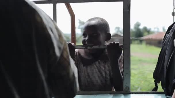 КИСУМУ, КЕНЯ - 21 мая 2018 года: Портрет маленького африканского мальчика, улыбающегося, держащегося за решетку. Милый мужчина проводит время на улице — стоковое видео
