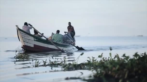 KISUMU, KENIA - 21 DE MAYO DE 2018: cámara lenta. Grupo de jóvenes africanos sentados en el bote y remando. Los pescadores están trabajando en el mar . — Vídeos de Stock