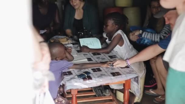 Κισούμου της Κένυας - 23 Μαΐου 2018: Τα παιδιά της Αφρικής και καυκάσιες γυναίκες, εθελοντές καθόμαστε στο φτωχόσπιτο, μιλώντας — Αρχείο Βίντεο
