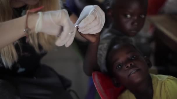 KISUMU, KENYA - 24 de maio de 2018: Mulher branca ajudando crianças da África. Feminino cortando suas unhas com tesoura . — Vídeo de Stock
