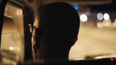 Arkadan görünüşü kel adam arabanın içinde küpeli. Araba throug boş yol geç gece sürme.