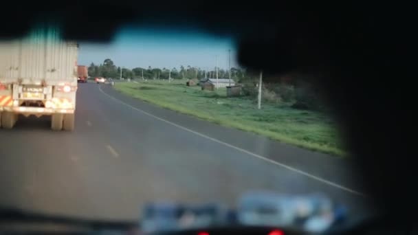 Vista desde el interior del coche. Coche que conduce a través de la carretera del campo, pueblo en África. Viajar en coche . — Vídeo de stock