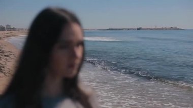 Genç bir kız sahilde odaklanmamış görüntüsü. O güneş gözlüğü üzerinde koyar, görüntü odaklı hale gelir ve tonlarında yansıtan deniz başlar