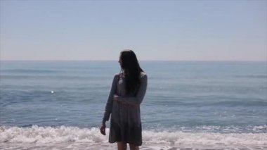 Güzel bir kız kendini deniz arka plan karşı tek kollu kucaklayan standları