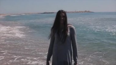 Plaj boyunca geriye yürüme elbiseli güzel bir kız. Ağır çekim