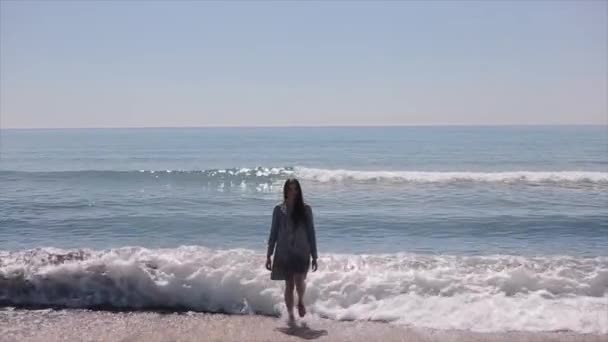 Un beau mannequin marchant pieds nus hors de la mer avec de grosses vagues se brisant sur le rivage. Mouvement lent — Video