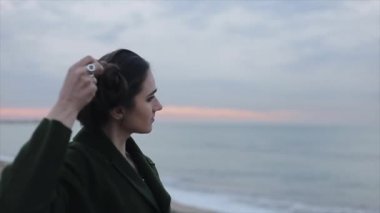 Denizin üzerinde güzel gündoğumu gökyüzü. Uzun siyah saçları geri alma ve manzarayı güzel bir kızın yan yarım vücut görünümü. Kızdan doğaya değişen odak