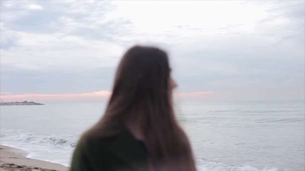 一个美丽的女孩看着侧面反对日出天空和海洋背景的密切视图。女孩转过头, 直视着。从自然到模型的焦点转移 — 图库视频影像