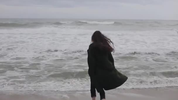 Uma linda garota corre descalça para o mar frio, toca a água e foge — Vídeo de Stock