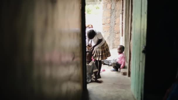 Kisumu, kenya - 15. Mai 2018: Afrikanische Kinder sitzen in der Nähe des Hauses. ein kleines Mädchen kämmt, flechtet ihren Schwestern die Haare. — Stockvideo