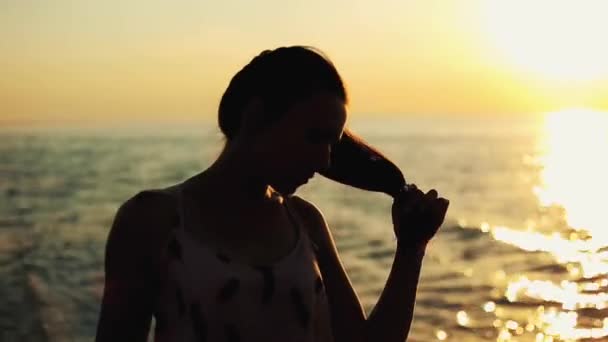 Uma linda garota está brincando com seu rabo de cavalo e pensando em algo. Um retrato de meio corpo. Vista panorâmica do céu do pôr do sol sobre o rio — Vídeo de Stock