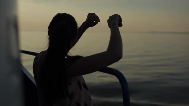 Krásná dívka stojí na palubě osobní lodi s náručí na zábradlí a má výhled na řeku večer. Boční pohled — Stock video