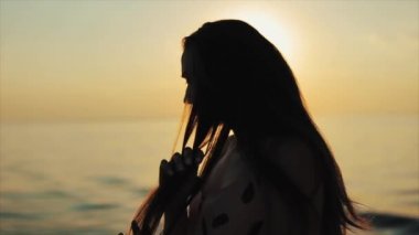 İçinde belgili tanımlık geçmiş gün batımında nehir ile saç teli ile oynarken güzel bir kız bir yakın yan görünüm