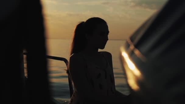 ポニーテールの美しい少女は、観光船の甲板の上に立つし、遠くに見えます。夕暮れの川。船のパーツは、焦点がずれています。 — ストック動画