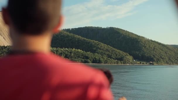 A close back blurred view of a man looking at the river and mountains — Stock Video