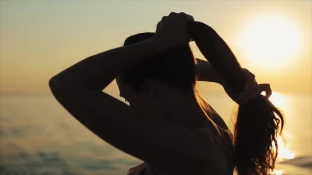 바다에 아름 다운 석양의 파노라마를 즐기는 포니 테일을 만드는 아름 다운 여자의 가까운 측면 보기 — 비디오