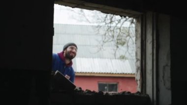 Balyozla bir duvar breaking. Düşen tuğla. Koruyucu gözlük ve mavi tulum giyen bir işçi. İçinde görünüm.