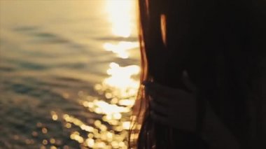 Uzun kahverengi saç ve su günbatımı yansıması