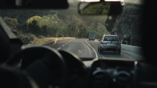 Barcelona, España - 27 de abril de 2018: Vista trasera de un camión y un coche que baja por la carretera de montaña con curvas mientras el sol brilla intensamente — Vídeo de stock