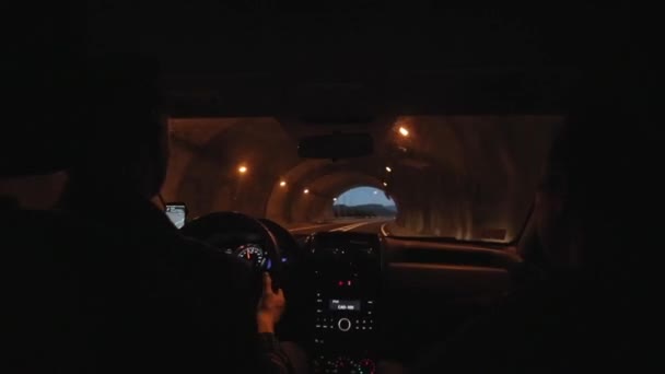 Familie paar reist met de auto in de avond. De auto gaat via een tunnel en rijdt op een bochtige bergweg. Achteraanzicht — Stockvideo