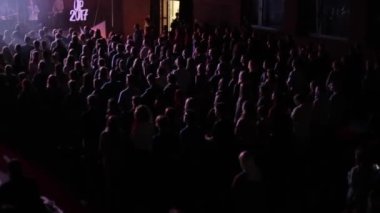 Bir sürü genç insan ayakta ve bir konserde alkışlar yukarıdaki bir bakış. Mavi ışık