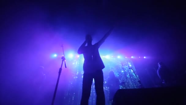 Un bărbat cu o trupă cântând pe scenă. Un cântec rapid. Lumini violet. Fum — Videoclip de stoc